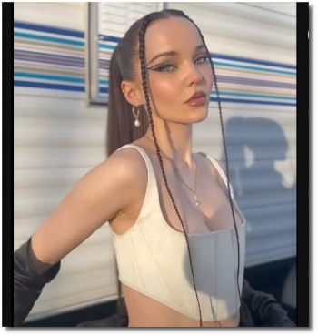 Dove Cameron in a ponytail with shadow projected and arms extended behind her (video posted 5 Dec 2022)
